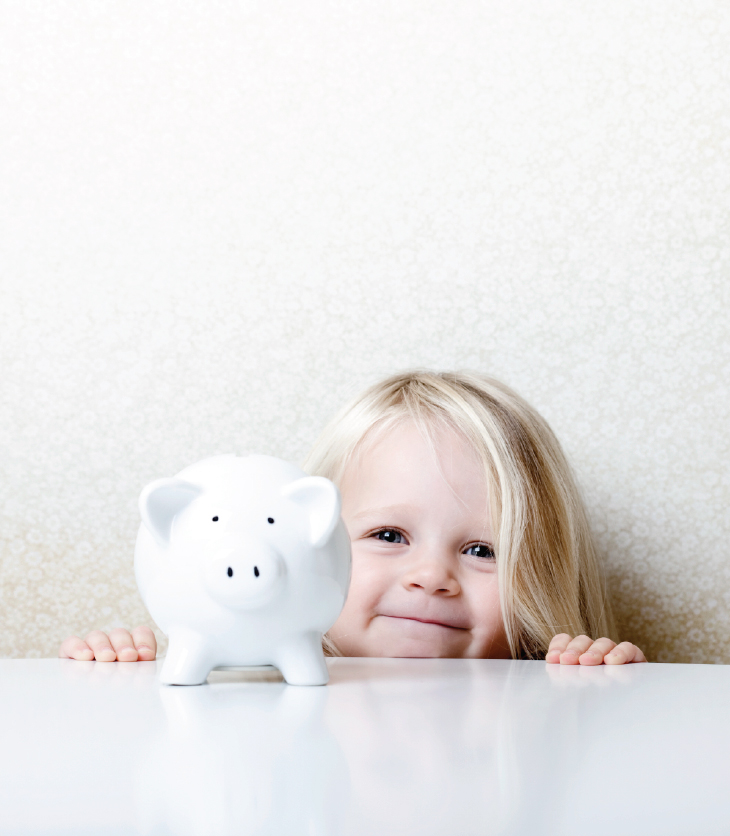 Young, happy girl standing with her piggy bank